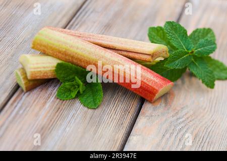 Fresh rhubarb and mint leaves on a wooden table Stock Photo