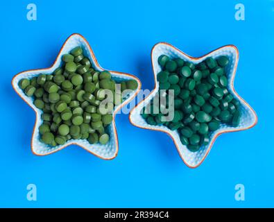 Spirulina algae powder and tablets on gray background from top view Stock Photo