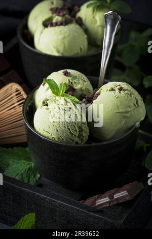 Matcha mint ice cream with chocolate chunks in a black bowl Stock Photo