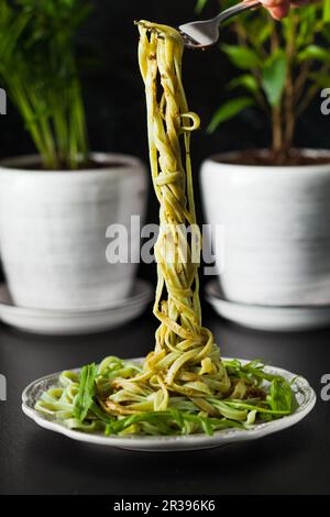 Pasta with arugula and pesto on the plate, black table Stock Photo