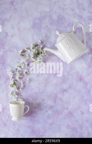 Cherry blossom flowers pouring from teapot into a cup Stock Photo