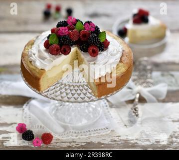 Vegan lemon sponge cheesecake with a baked quark layer decorated with soy cream, raspberries and blackberries Stock Photo
