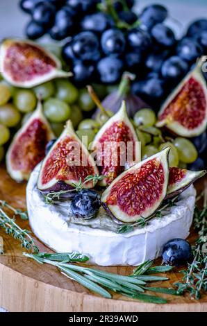 Cheese Camembert with figs, honey, grapes and fragrant herbs Stock Photo