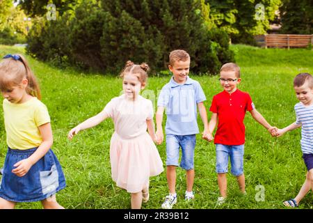Group of children holding hands and playing outdoors game Stock Photo
