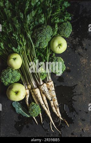 A bunch of parsley, broccoli florets and green apples on dark background Stock Photo