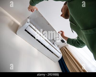 Man checks air conditioner. Repairman performs seasonal maintenance of air cooling and ventilation system. Stock Photo