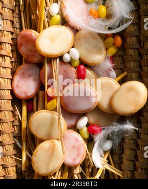 Glazed lemon and raspberry cookies in a woven basket with feathers for Easter Stock Photo