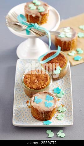 Mini carrot cakes baked in jars decorated with icing and fondant animals Stock Photo
