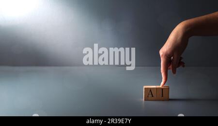 concept of AI in the workplace ,virtual assistant ,hand posing wooden block on grey background . Stock Photo