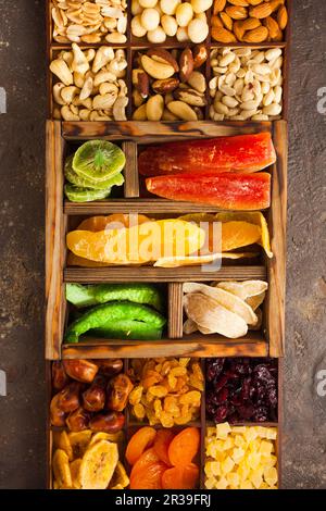 Variety of dried fruits and assorted nuts in a wooden box, view from above. Stock Photo