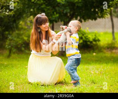 Happy family playing with a cat on green grass in garden Stock Photo