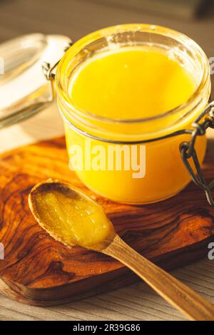 Wooden spoon with ghee - clarified butter in jar Stock Photo