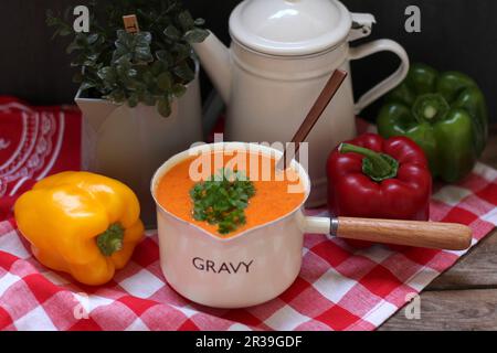 Pepper cream soup in a saucepan on a checked tablecloth Stock Photo