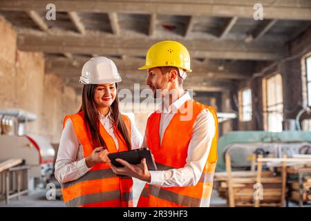 Smiling workers doing work using tablet at factory Stock Photo