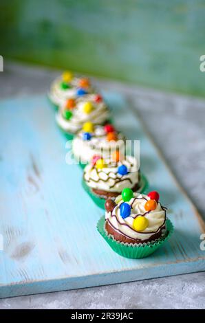 Chocolate cupcakes in green paper forms with butter cream and colored candies Stock Photo