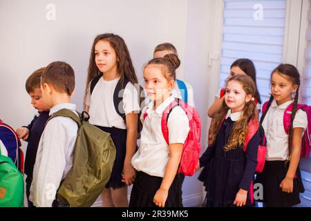 School children in uniform with backpacks going to class Stock Photo
