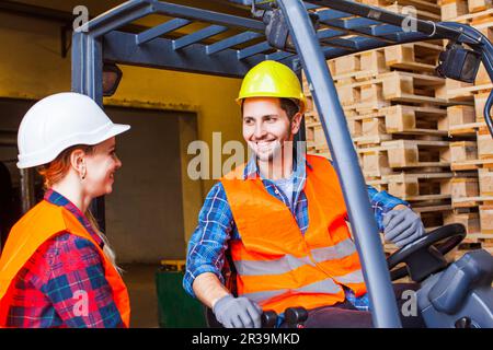 Warehouse manager checking order list. People in protective helmet, vest and gloves at factory. Stock Photo