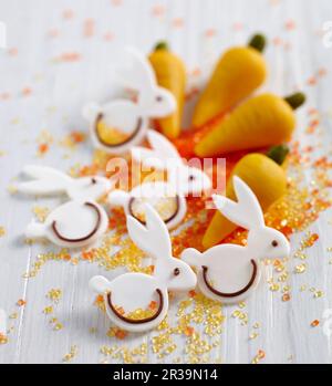 Edible Easter decorations: marzipan carrots and fondant bunnies with coloured sugar Stock Photo