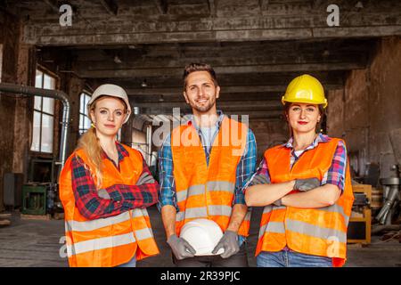 Factory workers in orange protective vests during work Stock Photo