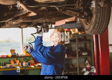 Young female mechanic works under the car Stock Photo