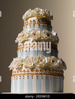 Easter Celebrations, three tiered white and teal striped wedding cake with camelia sugared flowers Stock Photo