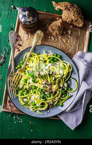 Zucchini spaghetti with feta and peas Stock Photo