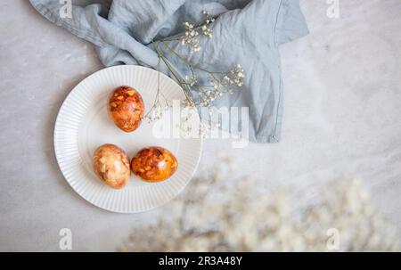 Easter Eggs In Basket, Naturally Dyed with Onion Skins, Flowers and Herbs on marble background Stock Photo