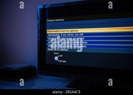 A modern TV displaying a message to update the PCMCIA module in order to access air and satellite signals. Press OK to continue with this advanced technology communication. Stock Photo