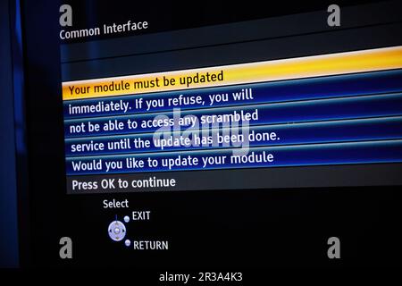 A modern TV set displaying a message urging the user to update their PCMCIA module in order to access air and satellite signals. Pressing OK will continue the technology process. Stock Photo