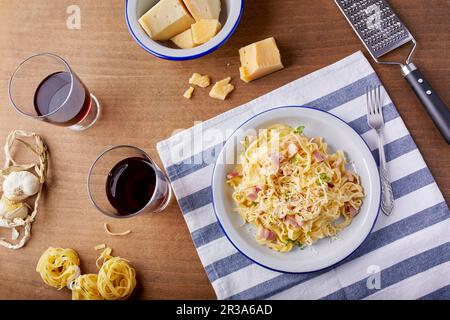 Homemade pasta Carbonara with parmesan cheese and a glass of red wine Stock Photo