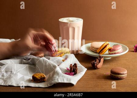 A hand taking macaron from a plate Stock Photo