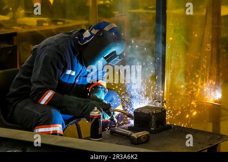 Man welding metal in a workshop, Tradesman working with welding torch Stock Photo