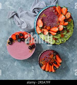 Vegan raw cheesecakes, top view with blueberry, cherry, matcha tea, orange, cashew cream, coconut butter and coconut milk, and base made of almonds, d Stock Photo