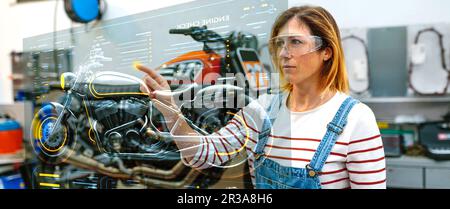 Female mechanic using hud panel screen with augmented reality hologram to review motorcycle Stock Photo