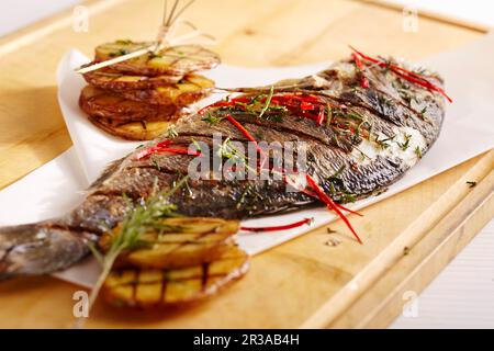 A whole, grilled bream with jalapenos, herbs and potatoes Stock Photo
