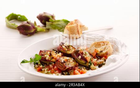 Grilled young artichokes with tomato and olive vinaigrette and white bread Stock Photo