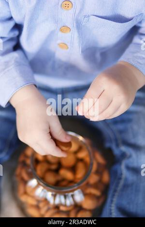 Child's hand reaching out to take cookies from a jar Stock Photo