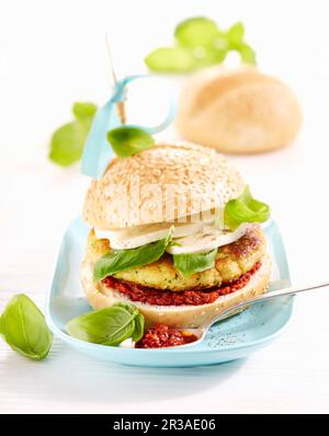 A vegetable burger with pesto rosso, mozzarella and basil Stock Photo