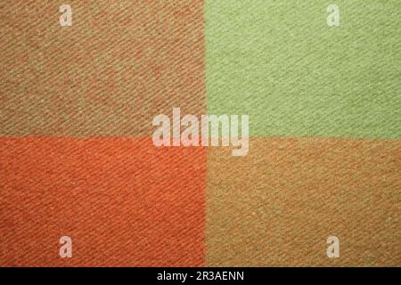 Soft and warm folded alpaca wool blanket. Green and orange wool plaid texture macro shot. Wool plaid Stock Photo