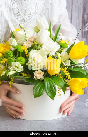 Bouquet of beautiful flowers with white peonies, roses, eustomas and yellow tulips, mimosa with gree Stock Photo