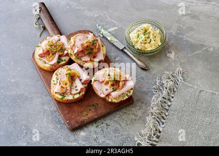 Rolls topped with Leberkäse (beef and pork meatloaf) with chive, onion and mustard butter in a jar Stock Photo