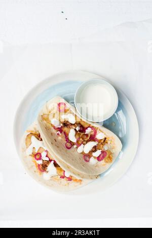 Beer battered fish fillets on wheat tortillas with fresh cabbage and carrot slaw, pickled red onion rings and sour cream Stock Photo