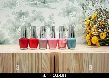 A lot of cans of nail polish of various colors on a wooden furniture with clear varnish Stock Photo