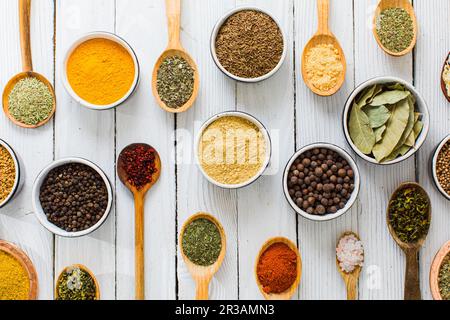 Assorted colorful spices and herbs in bowls and spoons Stock Photo