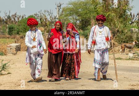 Men and women of the Rabari ethnic group in national dress are walking along the road. Stock Photo