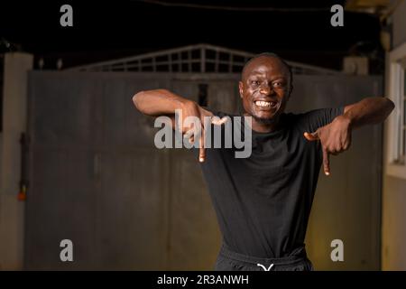 Excited young African man smiling pointing fingers aside at copy space for advertisement. Promotion and Advert concept Stock Photo