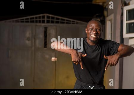 Excited young African man smiling pointing fingers aside at copy space for advertisement. Promotion and Advert concept Stock Photo