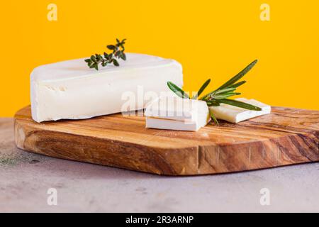 Pieces of camembert cheese on wooden cutting board Stock Photo