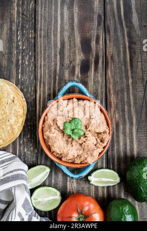 Refried beans with fried corn tortillas, avocados, tomatoes and fresh limes Stock Photo