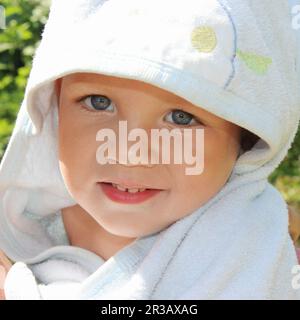 Closeup portrait of cute smiling baby boy in blue towel Stock Photo